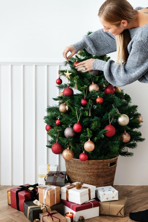 Blond girl decorating a Christmas tree with ornaments - 1231838