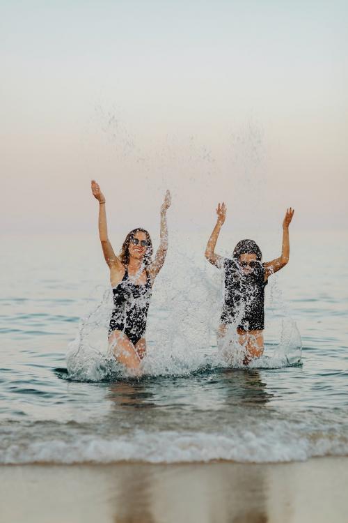 Cheerful girls splashing water at the beach - 1228342