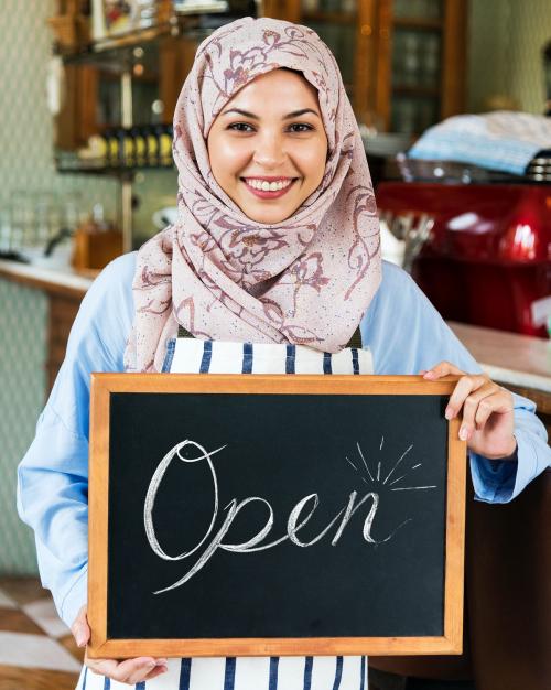 Islamic woman small business owner holding blackboard with smiling - 399986