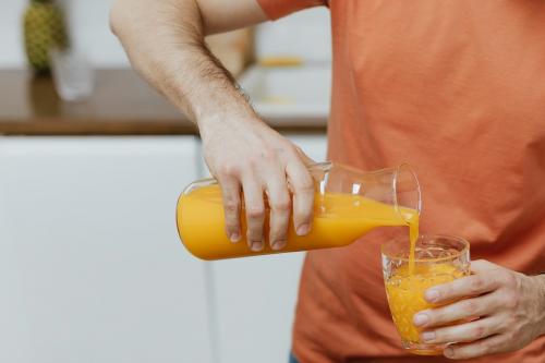 Man pouring orange juice into a glass - 937490