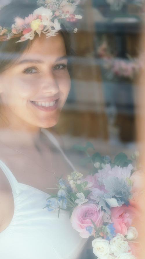 Smiling woman wearing a flower wreath and holding a bouquet of assorted flowers - 1207646
