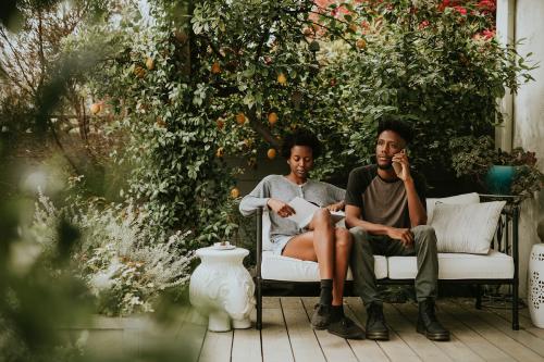 Black couple hanging in the garden with a book and a smartphone - 1211747