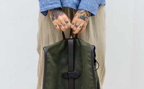 Tattooed hands holding a green bag - 1212501