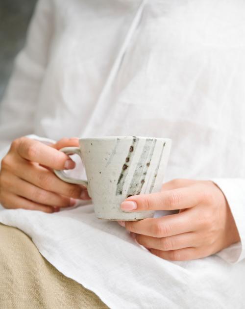 Woman in a white shirt holding a cup of coffee on her laps - 1212685