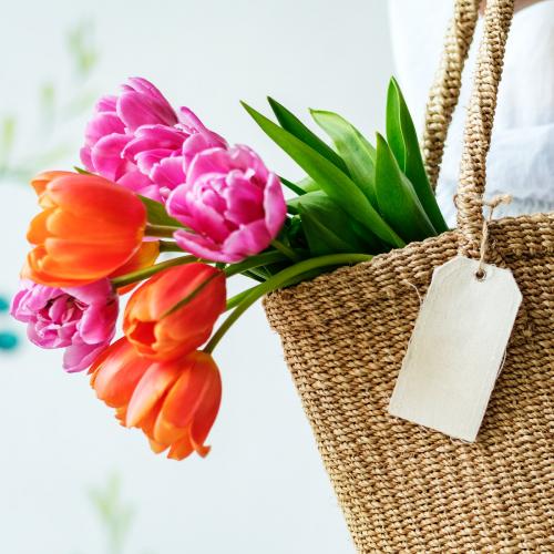 Woman carrying tulips in a wicker bag - 1207643
