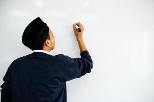 Young Muslim man writing on a whiteboard - 260532