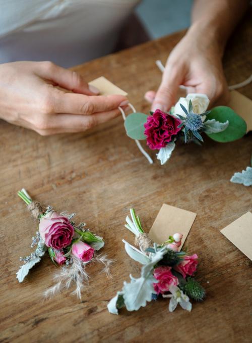 Hands creating boutonnieres with paper tags - 1207666