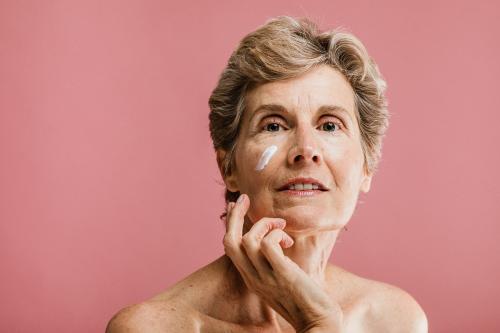 Elderly woman applying facial cream - 1203201