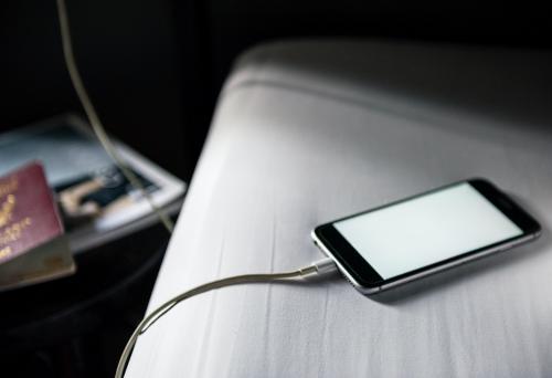 Closeup of mobile phone charging and lying on white fabric background - 8650