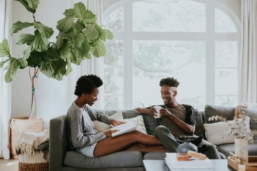 Black couple reading a book together on the couch - 1211644