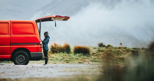 Woman standing by the red van in the highlands - 1077863