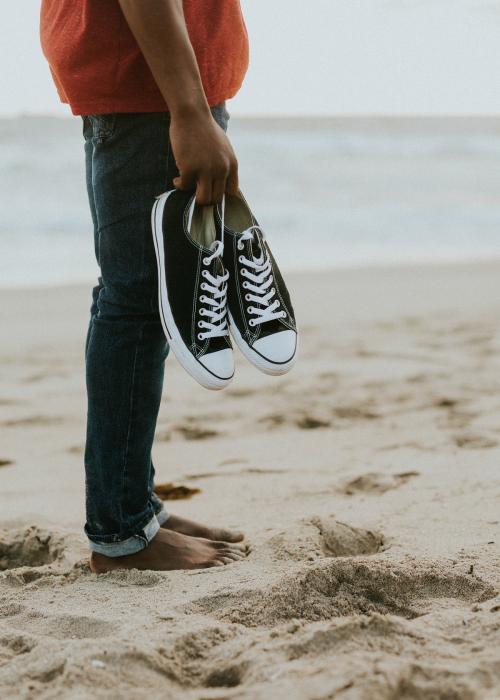 Black man carrying his shoes on the beach - 1079728