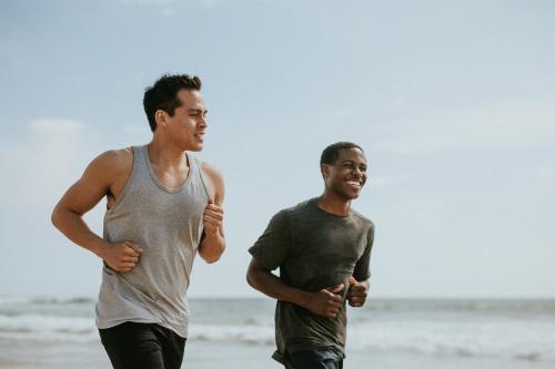 Happy friends jogging at the beach together - 1079969