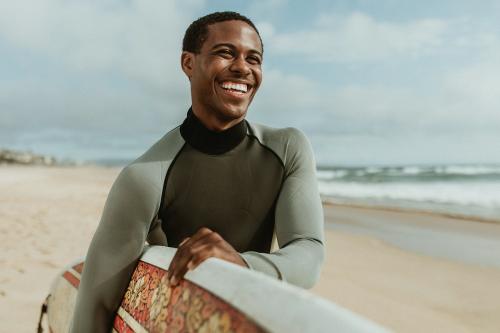 Cheerful man with a surfboard at the beach - 1079988