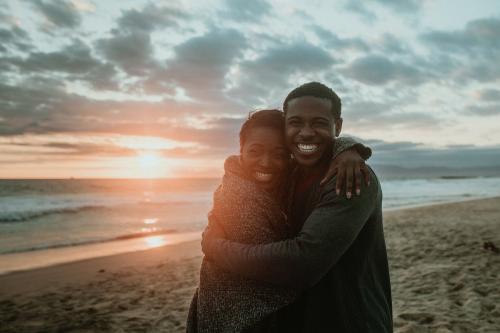 Cheerful couple hugging at the beach - 1080034