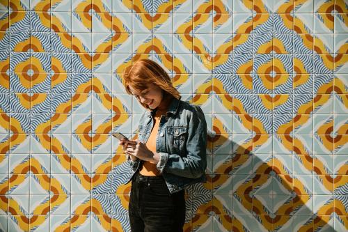 Woman using her phone at a modern patterned wall - 1198626