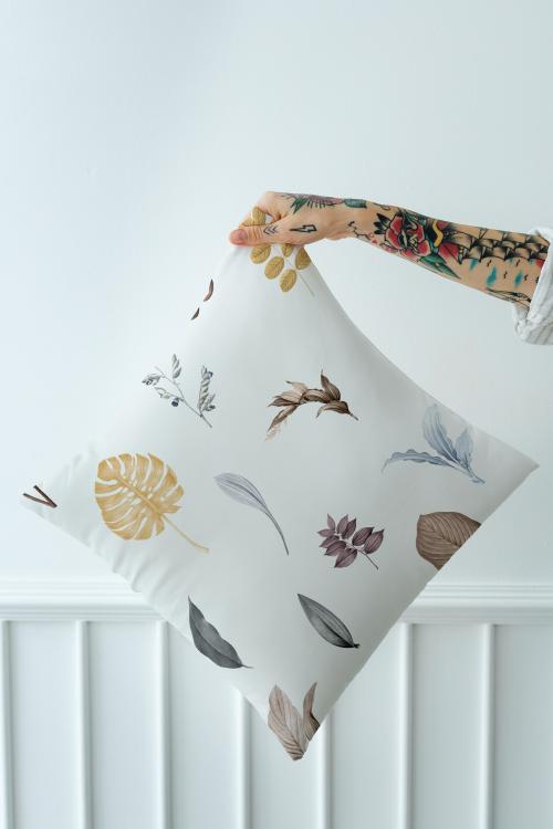 Tattooed woman holding a leafy pillow mockup - 1215297