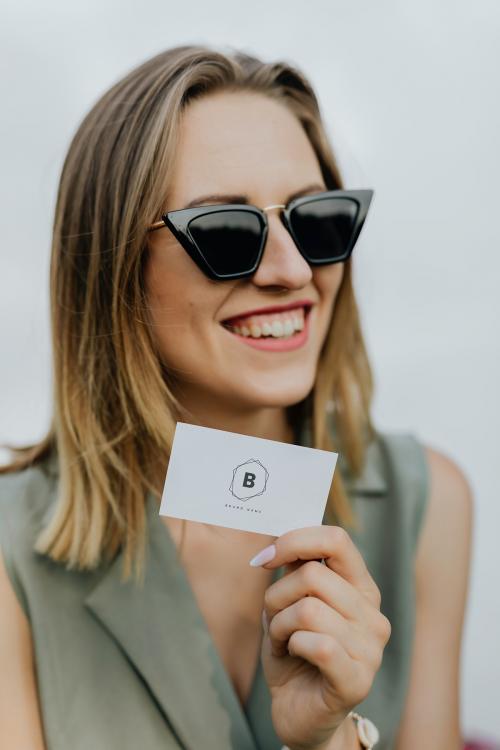 Friendly woman in sunglasses carrying a business card mockup - 1207948