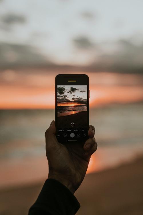 Man taking a picture of the sunset on the beach - 1079845