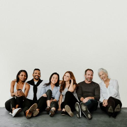 Group of cheerful diverse people sitting on a floor in a white room - 1201568