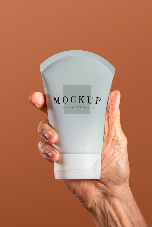 Hand holding a facial cream tube container mockup - 2209626