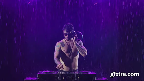Videohive A Sexy Male Dj with a Shiny Body From the Rain Plays on the Remote Control for Mixing Music in a 28773221