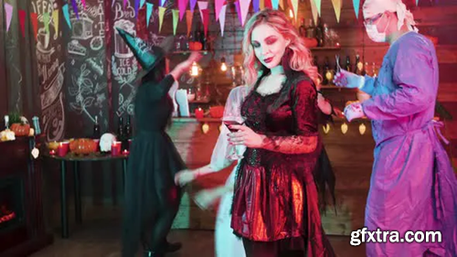 Videohive Sexy Witch Holding a Glass of Blood in Her Hands and Dances Slowly at a Halloween Party 23817448
