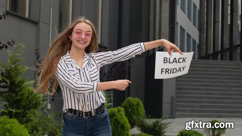 Videohive Happy Girl Holding Black Friday Inscription Text and Pointing on It. Shopping Mall Background 28654126